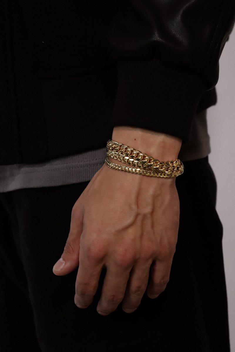 Stacked gold cuban bracelets on a wrist
