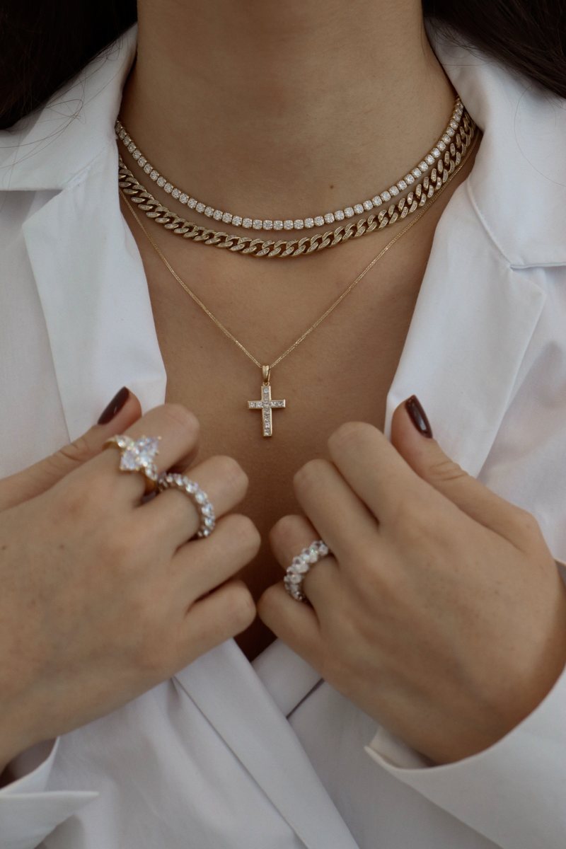 Layered tennis, cuban and cross necklaces with statement rings